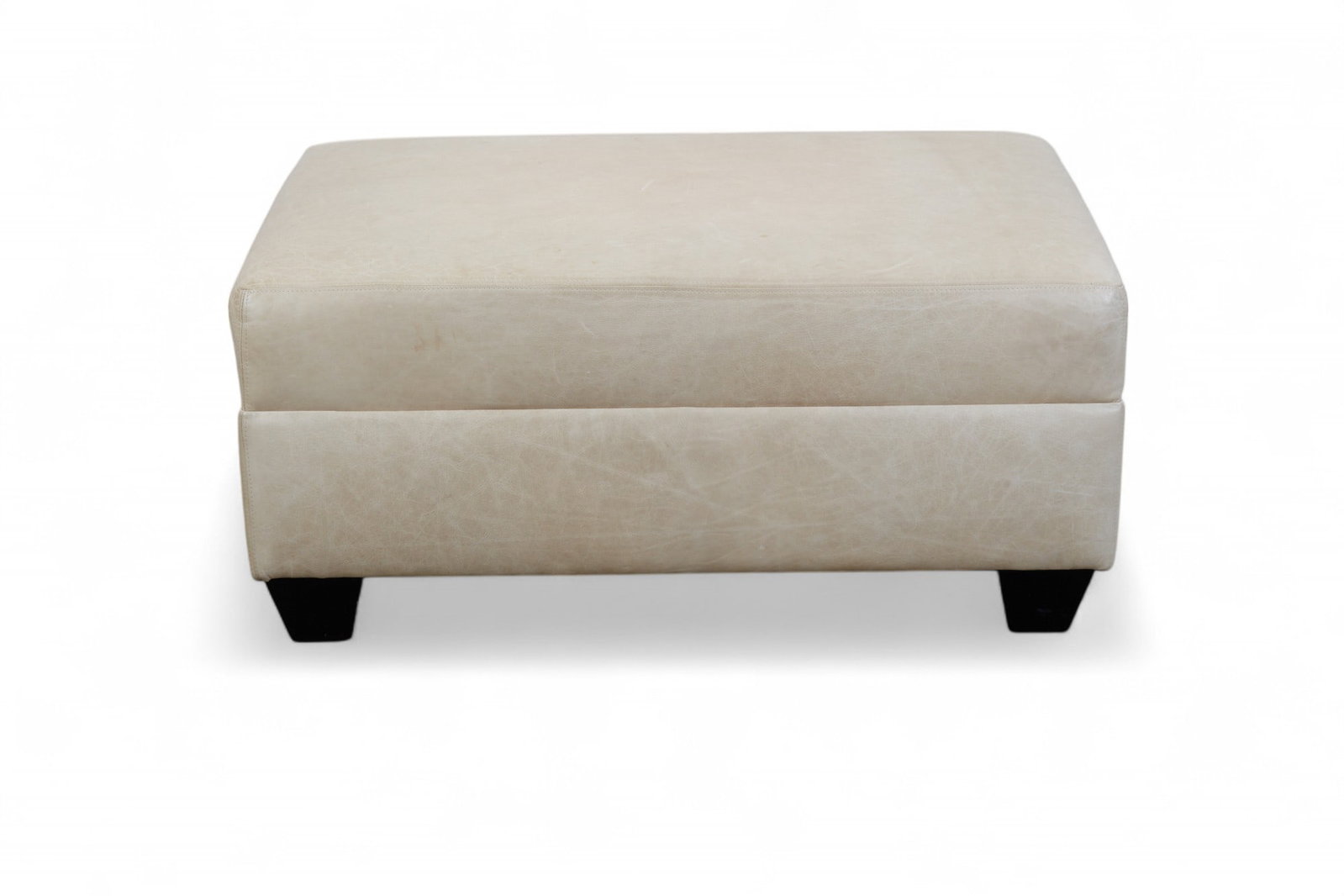 A contemporary leather ottoman: A contemporary leather ottoman Of rectangular form, upholstered in beige leather with stitched seams, raised on tapered dark wood feet. height 19in (48.3cm); width 41in (104cm); depth 30 1/2in (77.5cm