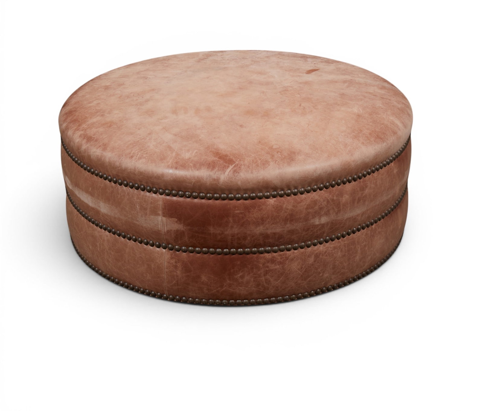 A circular close nailed tan leather upholstered ottoman, modern: A circular close nailed tan leather upholstered ottoman modern height 17in (43cm); diameter 41in (104cm)