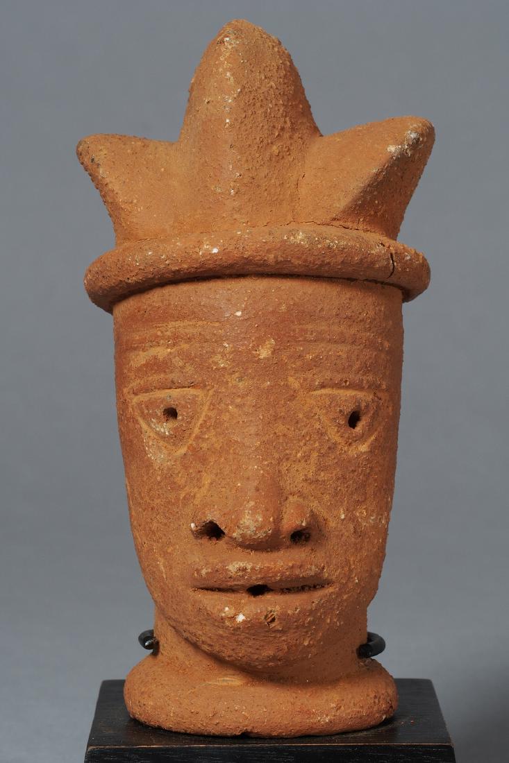 Nok Head Sculpture Tribal Art: Hollowed head displaying the typical features of Nok sculptures:an oblong face with a high forehead and eybrows.Its large,outlined eyes are almost rectangular,with deep set round pupils.The nose is fl