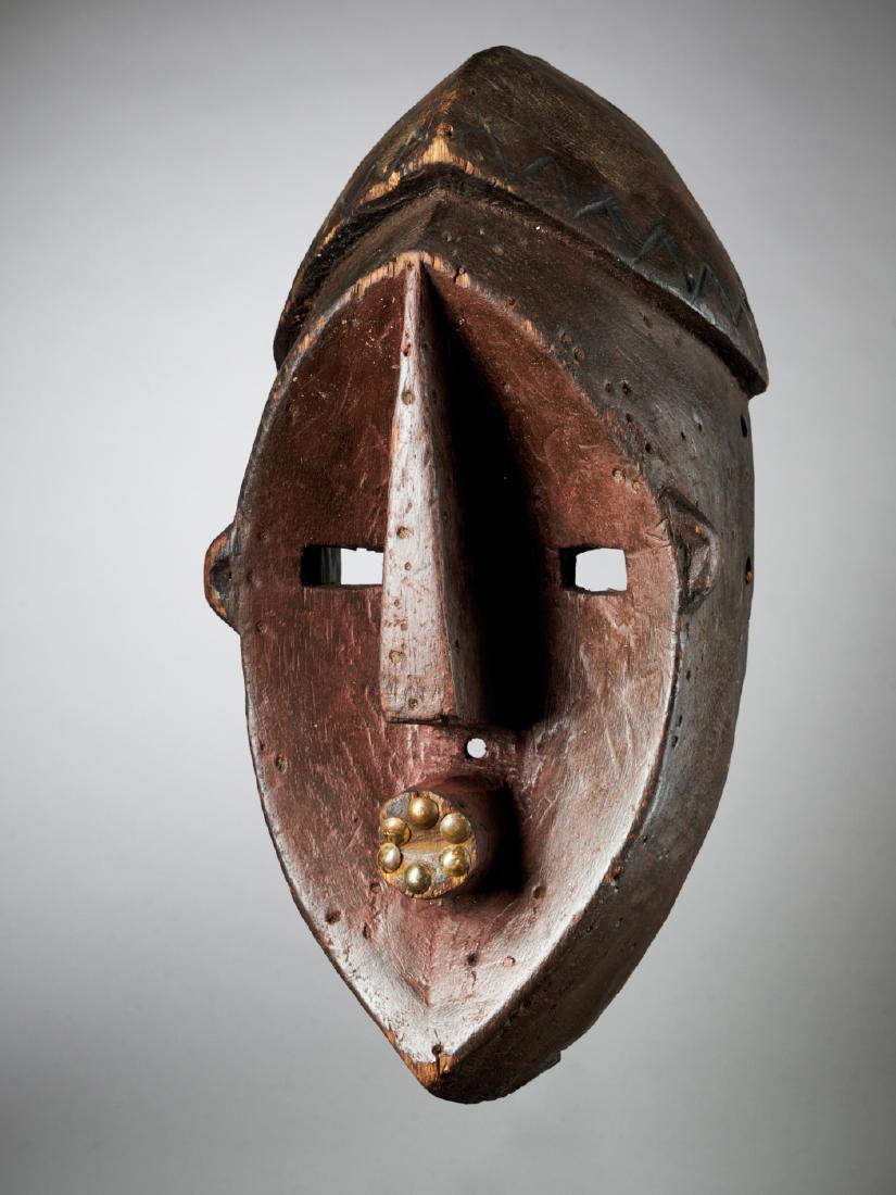 Lwalwa Facial Mask, Belgian Kongo - Tribal Art: This Lwalwa mask shows a stark and almost geometric design. The face is shaped and cleverly delineated by the transition between concave front and the rounded sides of the mask. Both the nose and tout