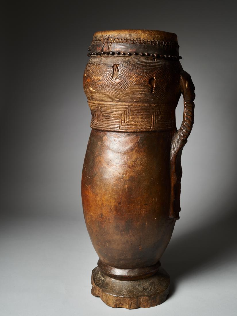 Drum Ngeende. Kuba People, DRC Provenance coll.Willy: A human face,in the form of a mask,finishes the handle in the form of a hand.Kuba drums with outward curved legs are rare and intended for the elite. The Kuba carved many different types of drums, man
