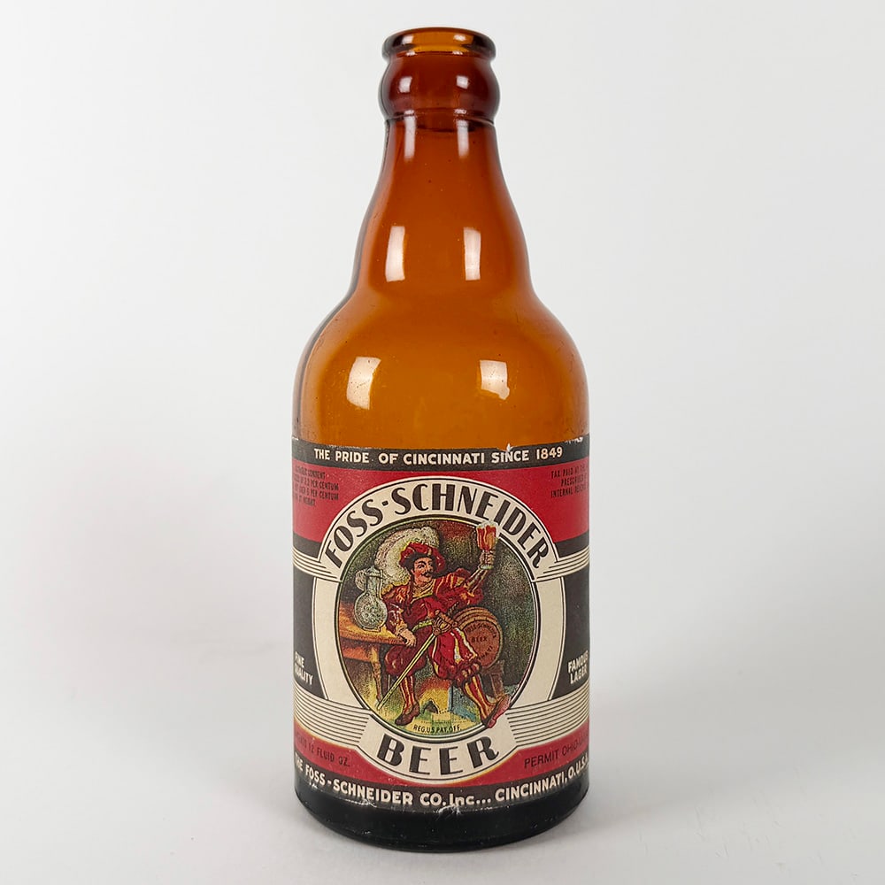 Foss-Schneider Beer Steinie Bottle Cincinnati OH: Circa 1930s Foss-Schneider beer bottle from Cincinnati, Ohio. Paper label featuring has a colorful illustration of a man with a drum. The label reads 'The Pride of Cincinnati Since 1849'. 