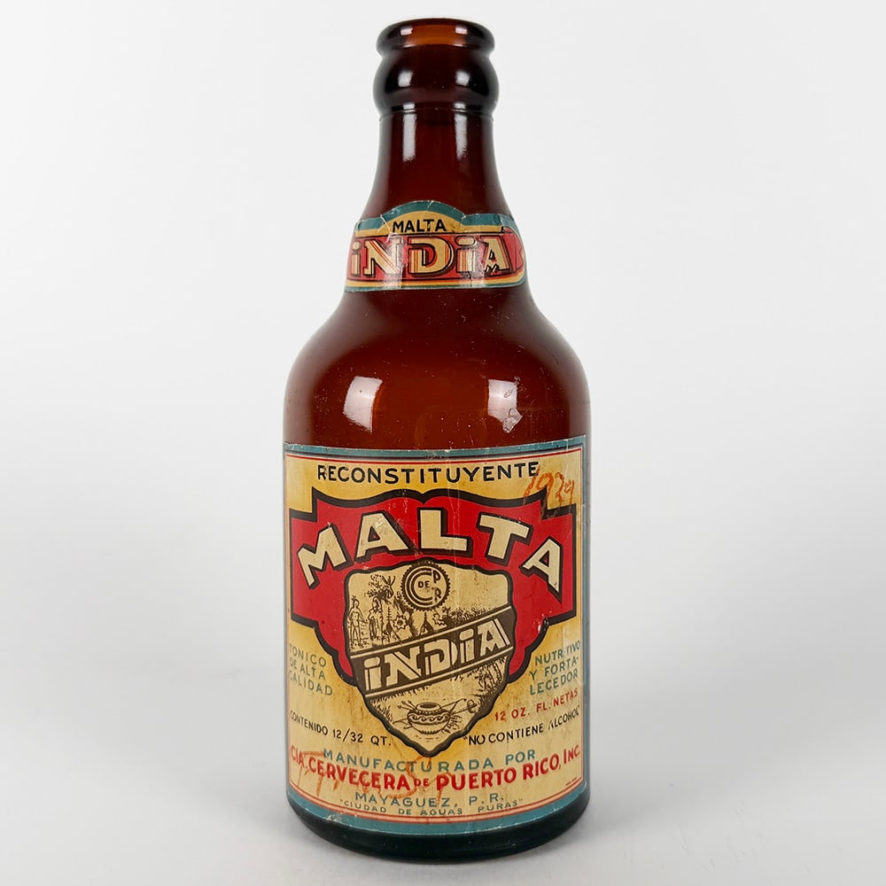 Malta India Beer Steinie Bottle - Puerto Rico: Circa 1930s Malta India beer steinie bottle from Puerto Rico. Cervecera de Puerto Rico. Features the original label with the Malta India logo and text in Spanish. 12 oz. 