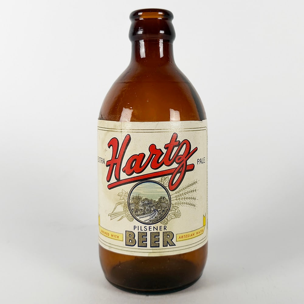 Hartz Pilsener Beer Stubby Bottle Tacoma WA: Circa 1950s Hartz Extra Pale Pilsener Beer bottle. Features a paper label with the Hartz logo and a landscape scene. Marked 'Brewed with Artesian Water' and 'Silver Springs Brewing Co., Ta