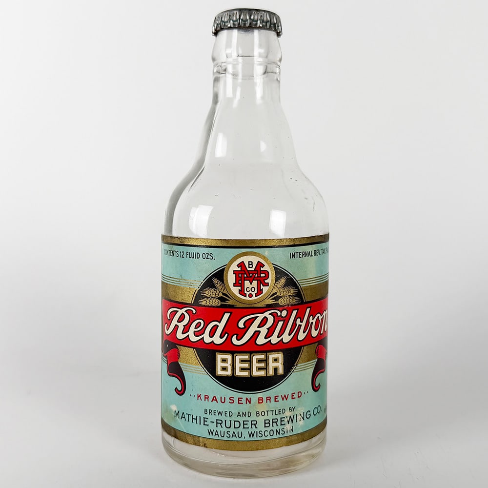 Red Ribbon Beer Steinie Bottle - Mathie-Ruder Brewing Wasau WI: Circa 1940s Red Ribbon Beer steinie bottle from Mathie-Ruder Brewing Co., Wausau, Wisconsin. Features the Red Ribbon logo and text on a light blue label with gold accents. 12 fluid oz.