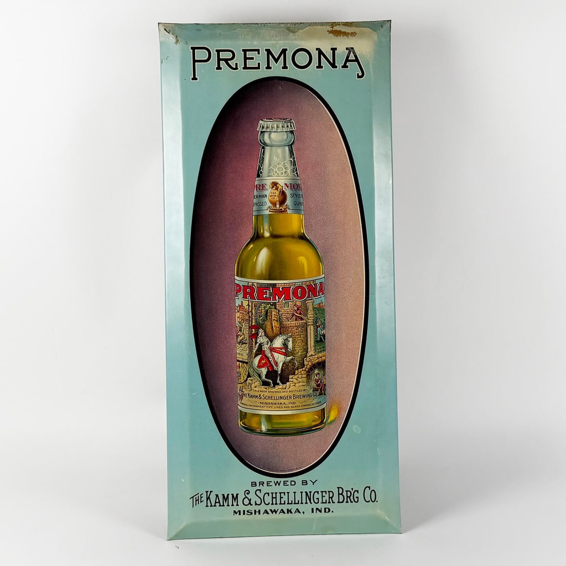 Premona Beer Advertising Sign Kamm & Schellinger Brewing Mishawaka IN: Pre-Prohibition Premona Beer advertising sign featuring a bottle of Premona beer. Made for Kamm & Schellinger Brewing Co., Mishawaka, Indiana. Oval outlined bottle pops against the baby blue 