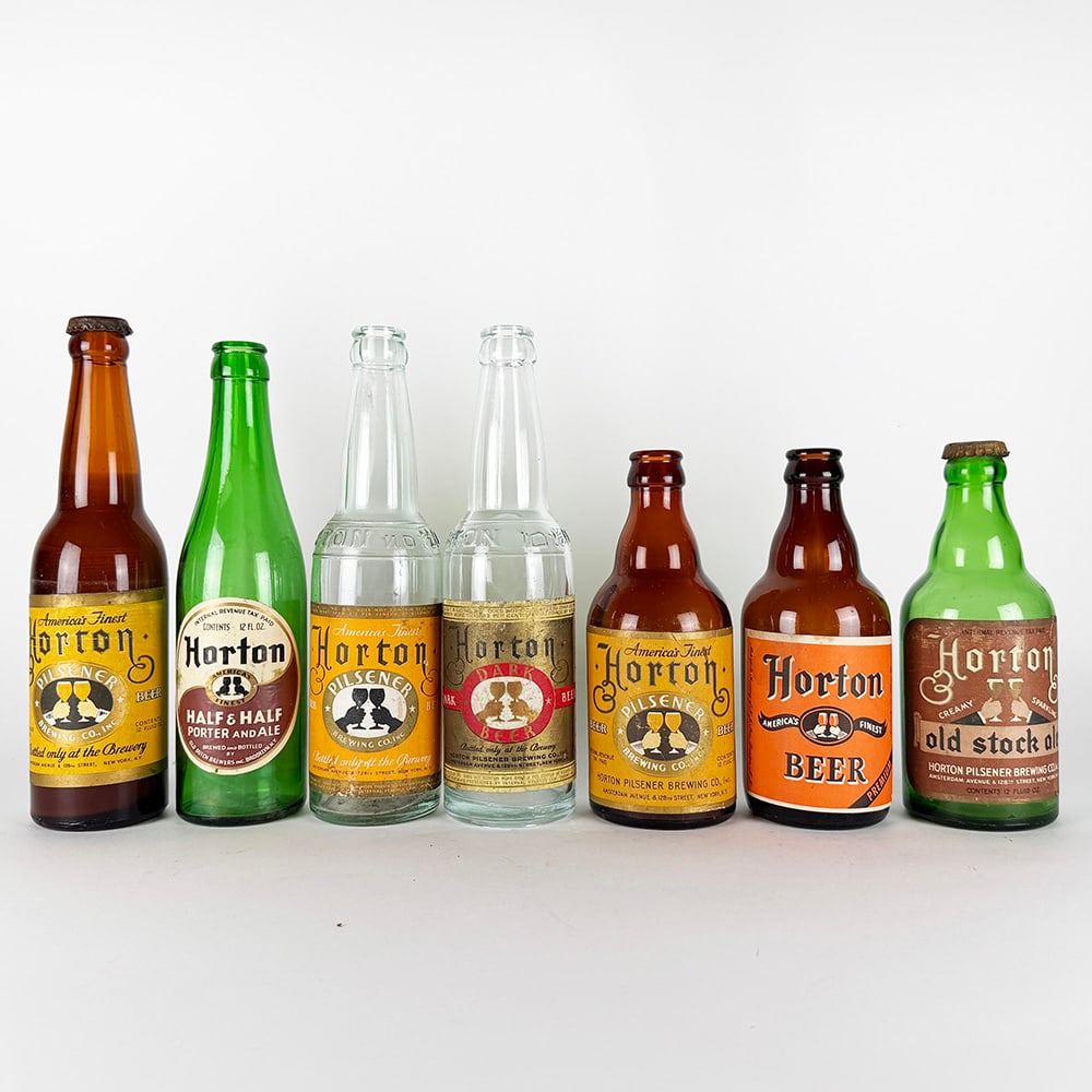 Seven Horton Labeled Beer and Ale Bottles, New York: Horton Pilsener Brewing Co., New York, New York. Circa 1930s–1940s. Seven labeled bottles in amber, clear and green glass, including Pilsener Beer, Dark Beer, Half & Half Porter and Ale, Old