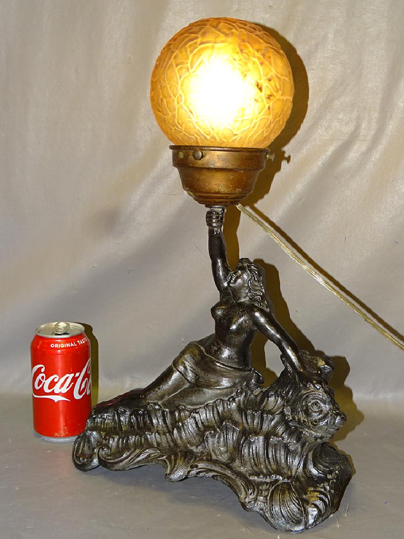 Figural Spelter Lamp with Nude and Dolphin: Figural Spelter lamp with amber ball shade of a nude lady riding a dolphin. 12" wide, 18" tall.