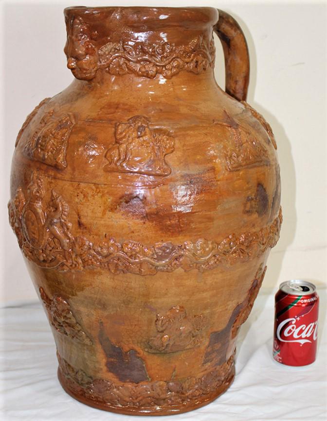 Large Redware Glazed Pitched with Heads and Windmills: Large redware glazed pitched with heads, windmills, a crest, etc. Looks to be in good condition. 14" wide, 21" tall, 16" deep.