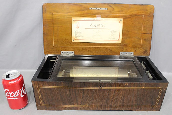Fine Antique 6 Tune Cylinder Music Box With Floral Inlaid Case: Fine antique 6 tune cylinder music box with floral inlaid case. Rosewood inlay 8" cylinder, all teeth are good. Has a few small chips on veneer missing (see photo). 17" wide, 5" tall, 8" deep.