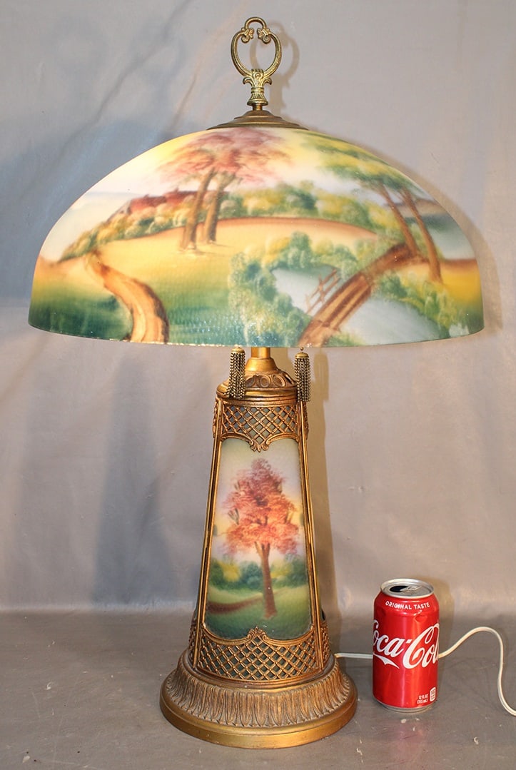 Antique Reversed Painted Table Lamp With Vivid Colors: Antique reversed painted table lamp with vivid colors. Has ocean woodland scene with a house on the water and light up base. Very pretty lamp. 17" wide, 26" tall.