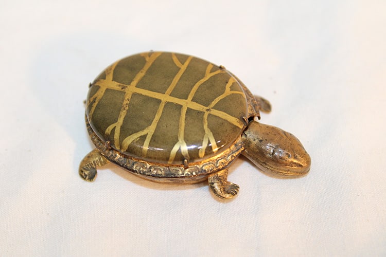 Unusual Brass Turtle With What Looks Like A Scroll Inside: Unusual brass turtle with what looks like a scroll inside. Has a hand painted porcelain top, head comes off, antique and different. About 2" long.