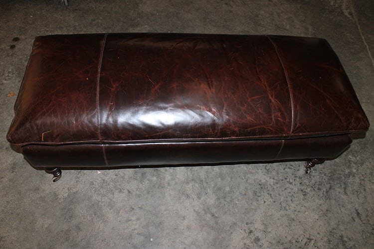Fine 50" Brown Leather Ottoman: Fine 50" brown leather ottoman with turned mahogany legs and brass casters. No rips or tears. Has some normal rubs from being used. 50" wide, 21" tall, 20" deep.