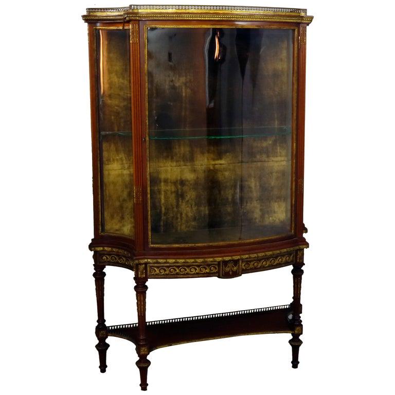 French Louis XVI Mahogany & Ormolu Locking Vitrine: An antique French Louis XVI vitrine features mahogany construction with pierced gallery over case with convex glass sides and single concave glass door opening to glass shelved interior, skirt with ca