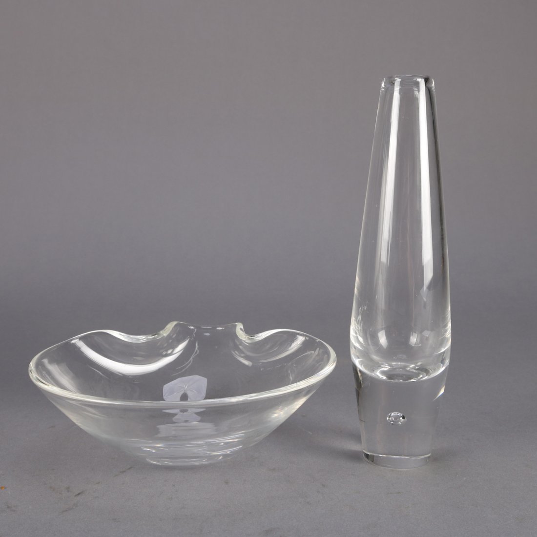 Signed Steuben Crystal Bud Vase & Bowl: An art glass Steuben bud vase and bowl, colorless, signed, 20th century.Measures - bud vase: 8" h x 2.25" w, bowl: 2.25" h x 6" w***IN-HOUSE SHIPPING & DELIVERY QUICK QUOTES AVAILABLE UPON REQUEST***