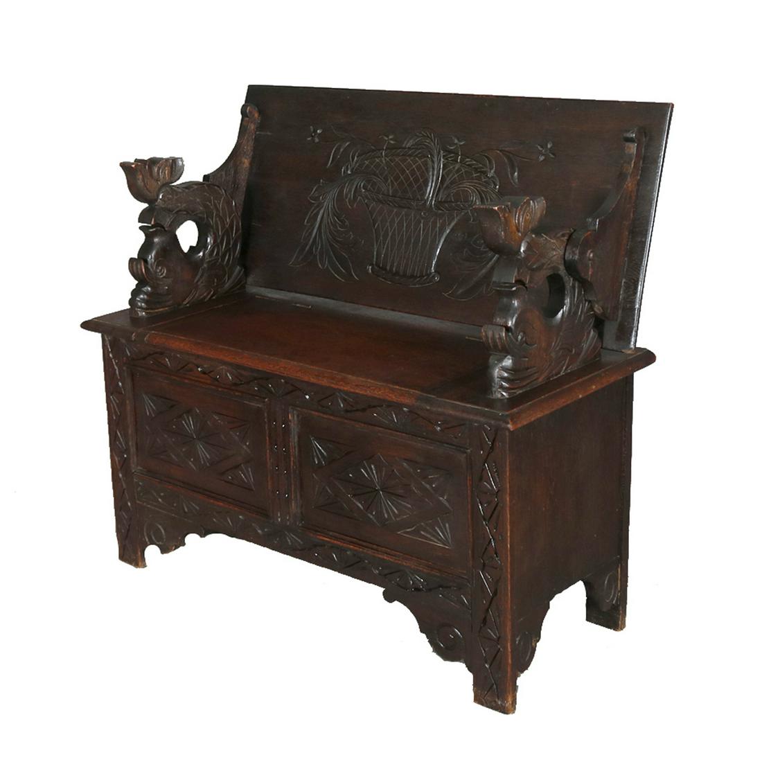 English Oak Carved Hall Seat, Convertible Table, Chest: English carved figural oak monks bench w/lift top seat & dolphin arms, carved panels and floral basket backrest, 19th C Measures - table: 33" h x 41" w x 17" d, bench: 39" h x 31" w x 13" d, 21" seat