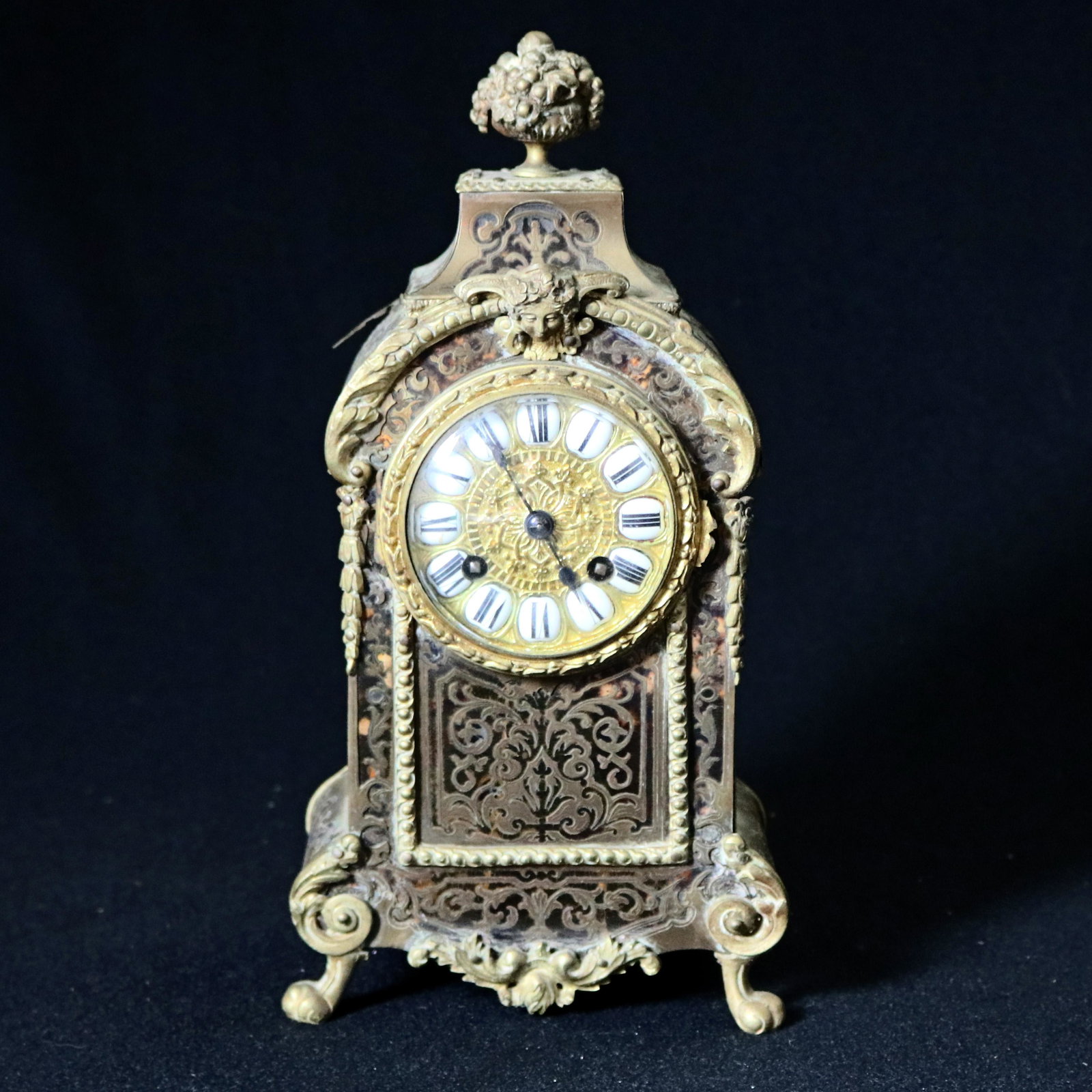 Boulle Bronze & Tortoise Louis XIV Style Clock: Antique French Louis XIV mantel clock offers casat fruit urn finial surmounting Boulle bronze and tortoise cased clock with Jenny Lind mask, Persian scroll and foliate style Boulle decoration, and rai