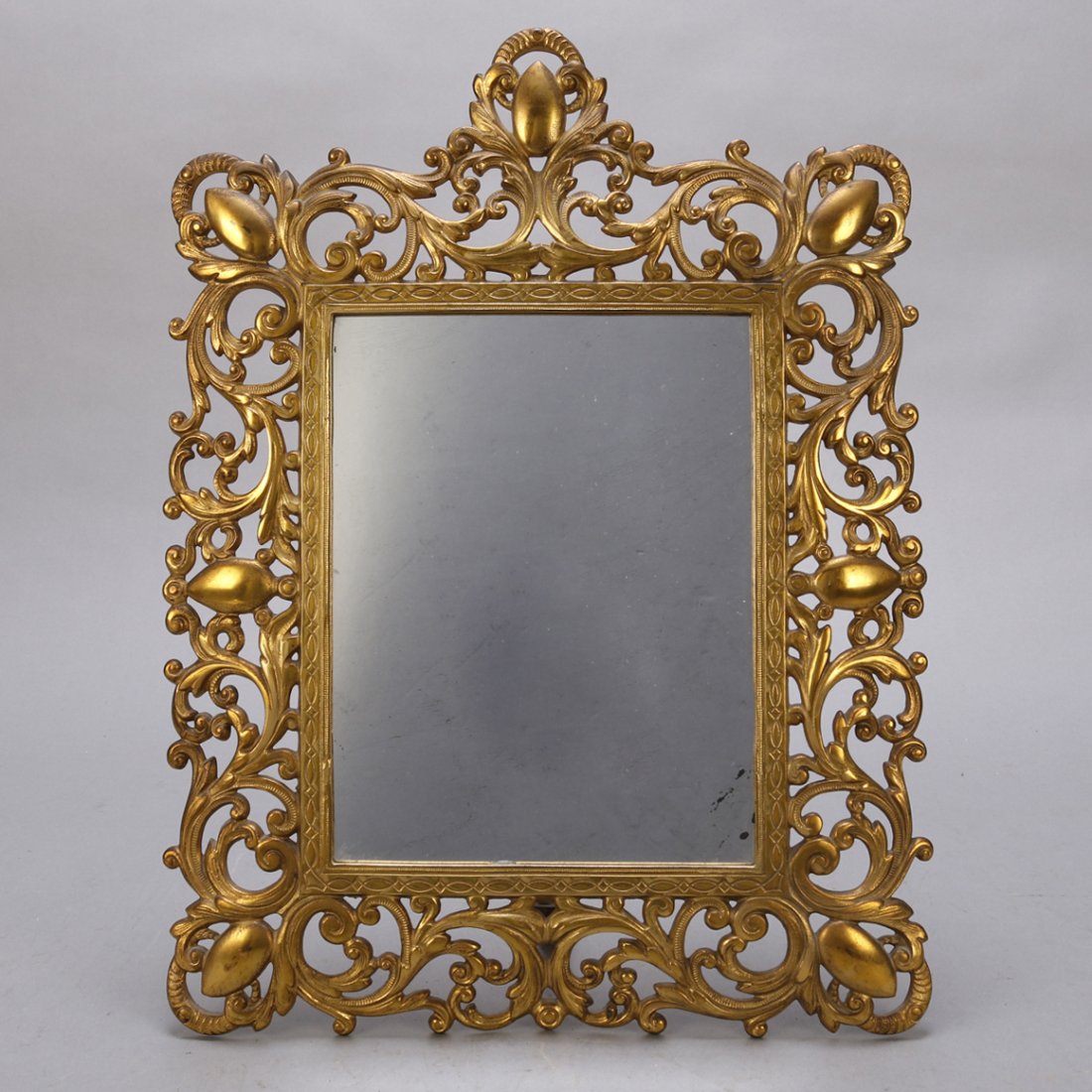 Antique French Gilt Metal Pierced Foliate Table Mirror: An antique French gilt metal tabletop vanity mirror offers pierced foliate form frame, circa 1900. Measures: Frame 17.5" H x 13" W x 5.5" D, los 9.5" H x 7" W. ***IN-HOUSE SHIPPING & DELIVERY QUICK QU
