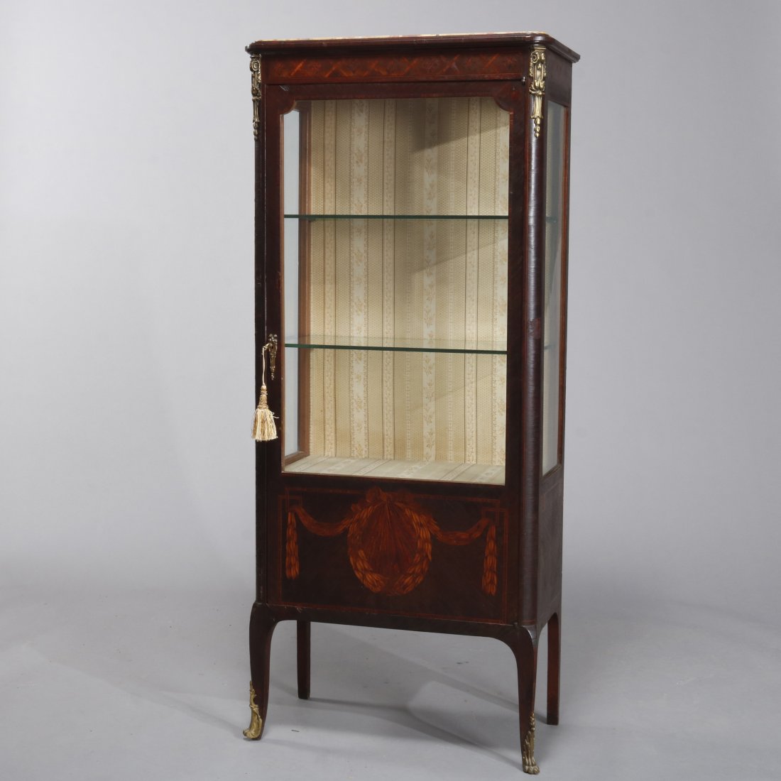 Antique French Louis XV Style Marquetry, Ormolu Vitrine: An antique French Louis XV style vitrine offers mahogany case with marble top surmounting mahogany case with scroll, foliate and garland marquetry, single glass door and foliate cast ormolu mounts, wi