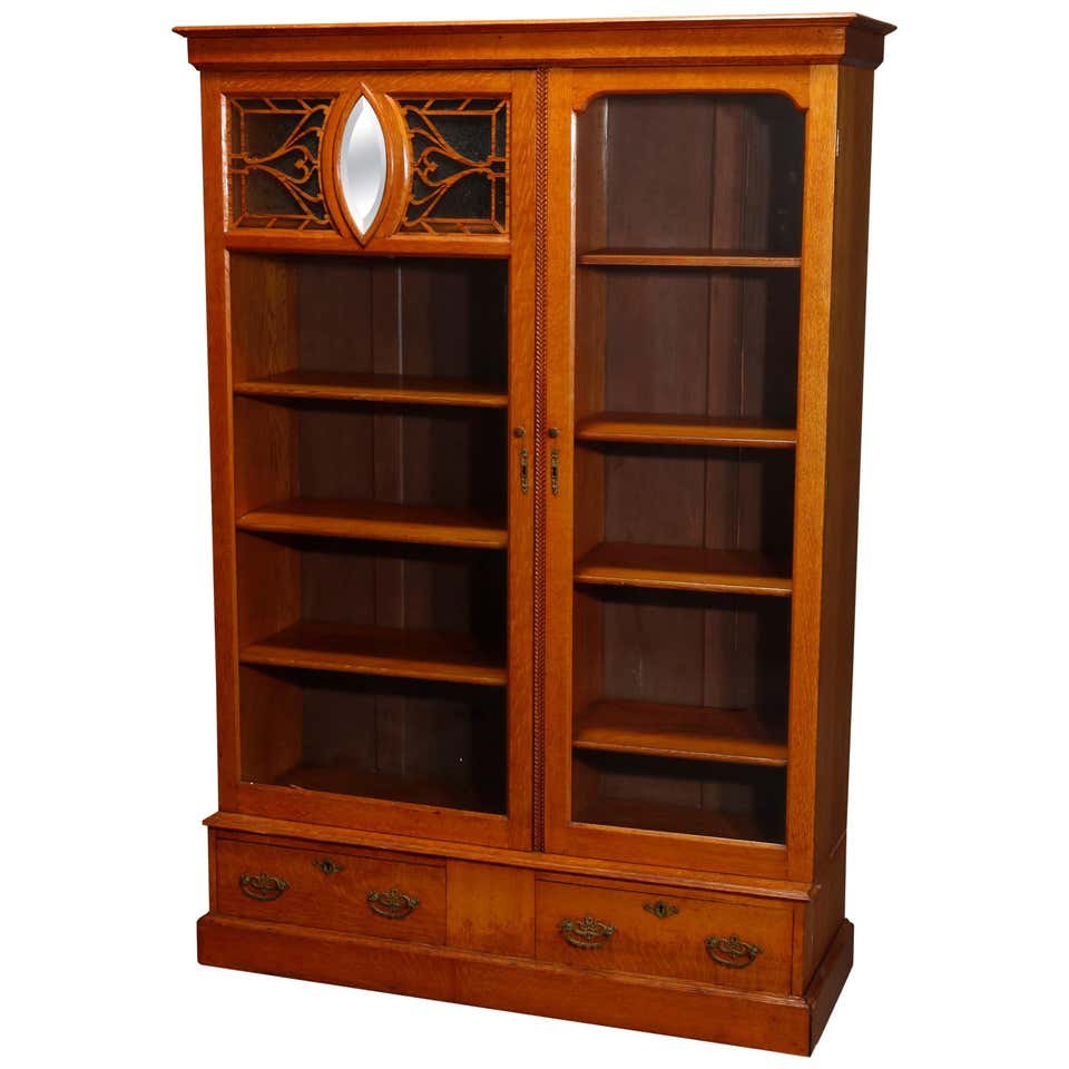 Antique Rockford Double Door Oak Bookcase, C 1920: An antique Arts & Crafts bookcase by Rockford offers quarter sawn oak construction with double glass doors, one with cutout filigree stylized floral element having central beveled mirror and surmounti