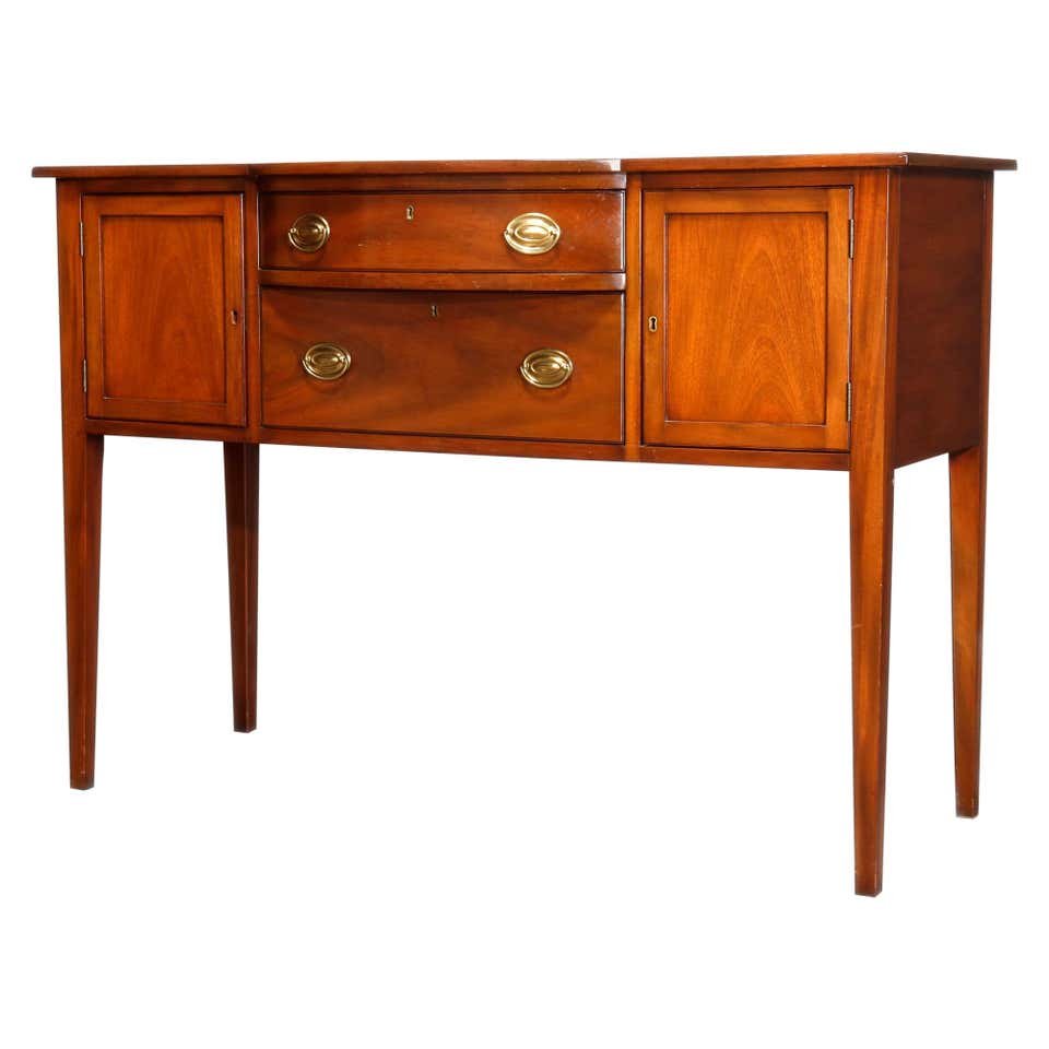 Kittinger Colonial Williamsburg Mahogany Sideboard: A vintage sideboard by Kittinger of the Williamsburg Adaptation line offers mahogany construction with shaped top surmounting central stacked drawers having flanking cabinets with paneled doors, raise