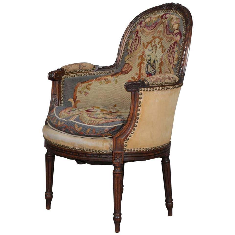 French Louis XV Carved Mahogany & Tapestry Armchair: An antique French Louis XV style armchair features mahogany frame with carved relief ornament and scroll form arms, tapestry upholstered with central portrait with surrounding foliate motif, circa 187