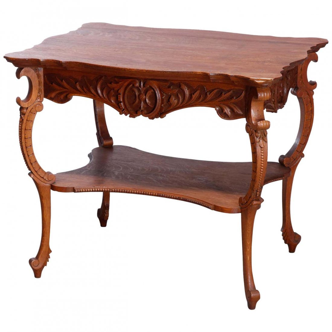 Antique RJ Horner School Oak Parlor Lamp Table, c 1900: An antique parlor lamp table in the manner of RJ Horner offers quarter sawn oak construction with shaped top surmounting skirt with foliate and scroll elements, raised on scroll form cabriole legs and