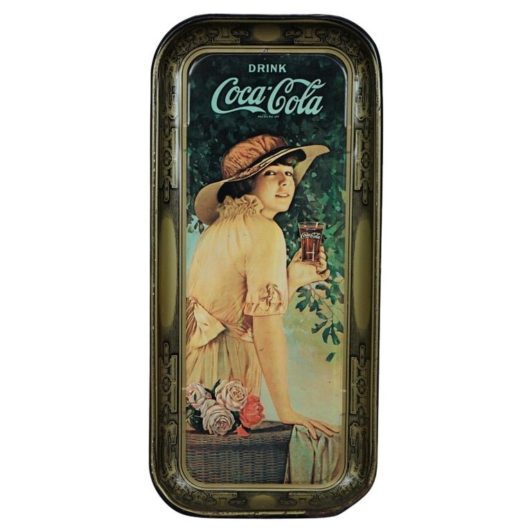 Vintage Tin Coca-Cola Advertising Tray 20th C: An vintage metal Coca-Cola advertising tray offers metal construction with woman with glass of coke in outdoor setting, decorated surround, 20th century. Measures- 18.75''H x 8.5''W x 1''D. *** OPTION