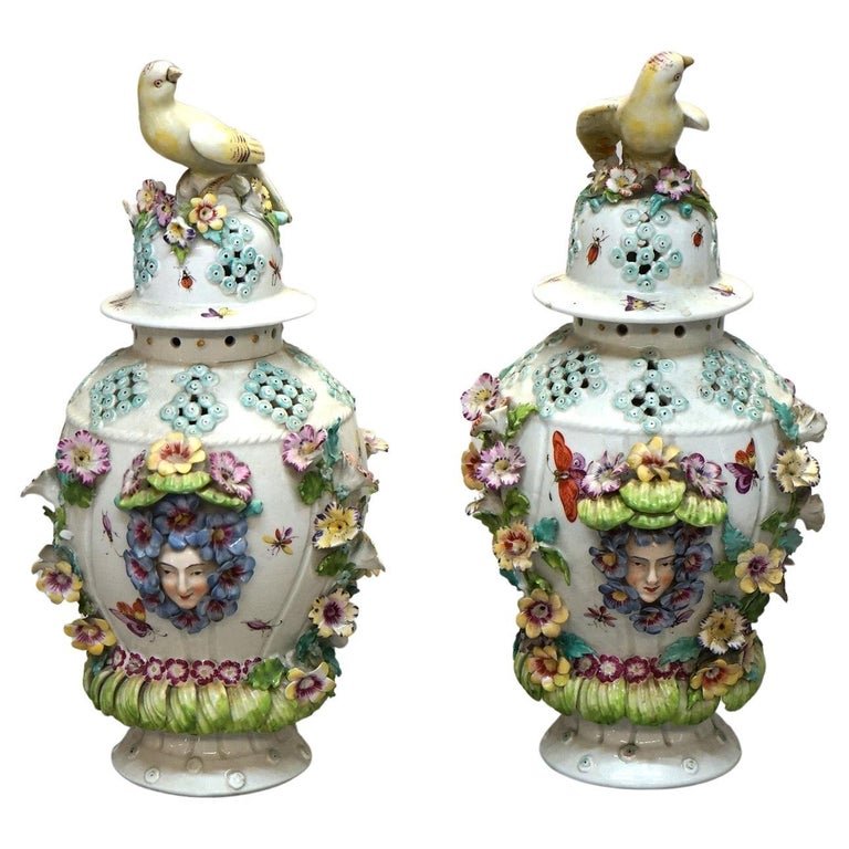 Antique 12" Dresden & Meissen School Figural Porcelain Covered Urns Circa 1890: An antique pair of German porcelain covered urns in the manner of Dresden or Meissen offers porcelain construction with figural lids with bird finials over vessel with applied and hand painted flowers