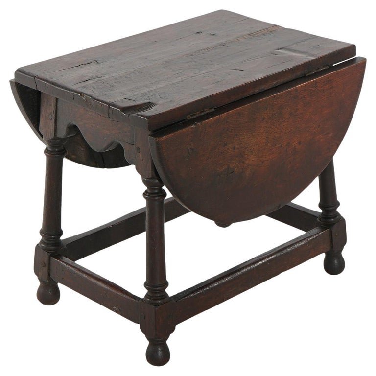 Early Antique English William & Mary Walnut Drop Leaf Side Table 16th C: An early antique English William and Mary side table offers walnut construction with top having drop leaves and raised on slayed legs with cross-stretchers, 19th century. Measures - 18"h x 19.75"w x 1