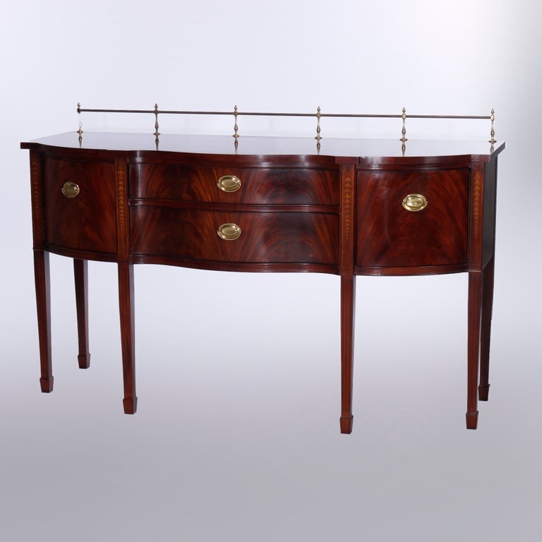 Hepplewhite Satinwood Inlaid Flame Mahogany Sideboard by Thomasville, 20th C: A Hepplewhite style sideboard by Thomasville offers flame mahogany construction in serpentine form with top having brass rail over case with central double drawer stack and flanking blind cabinets, ra