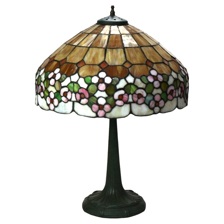 Arts & Crafts Era Leaded Slag Glass Table Lamp with Floral Shade C1920: A antique slag glass table lamp from circa 1920, featuring a stunning floral pattern. The lamp showcases a dome-shaped shade with intricate stained glass work in hues of brown, pink, green, and white,