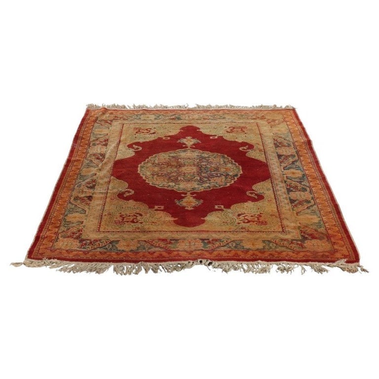 Oushak Turkish Wool Rug C1920: An antique Oushak rug from Turkey, dating to circa 1920. This rug features a central medallion design with floral patterns, set against a red tone background. The border showcases a blend of earthy to