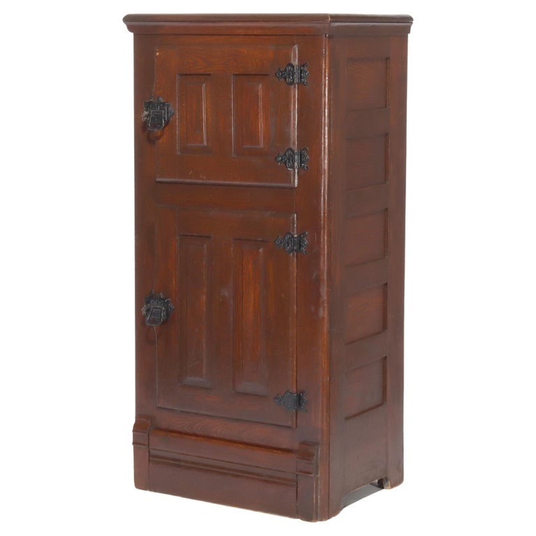 Antique Oak Raised Panel Ice Box C1900: This antique oak ice box, dating from around 1900, features a classic raised panel design. It is crafted from solid oak, showcasing the rich grain and durability typical of the period. The hardware is