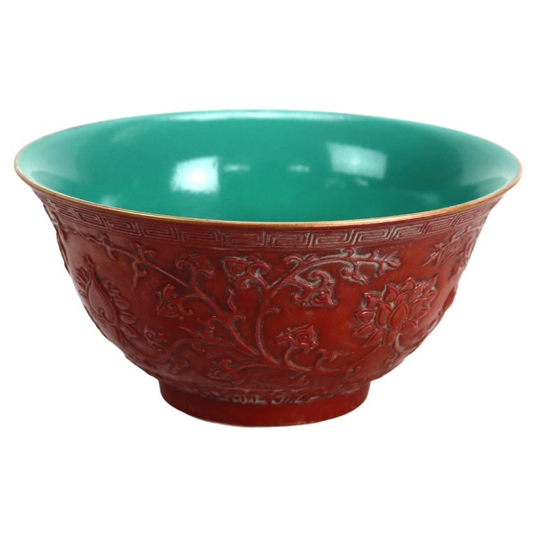 Chinese Floral Carved in Relief Pottery Bowl Signed 20th C: A Chinese pottery bowl from the 20th century, featuring intricate floral carvings and relief work. The exterior showcases a red hue with detailed floral patterns, while the interior is glazed in turqu