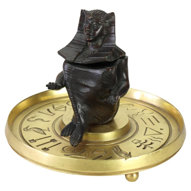 Egyptian Revival Pharaoh Bronze & Brass Inkwell With Glass Insert c1880: This Antique Egyptian Revival inkwell, crafted from cast bronze and brass, dates to approximately 1880. The central bronze figure, depicting a pharaoh or deity adorned with a nemes headdress, is intri