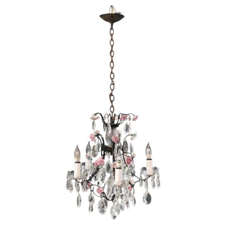 Vintage Crystal, Porcelain & Ebonized Iron 5-Light Floral Chandelier C1940: This vintage five-light chandelier, dating to approximately 1940, features an ebonized iron frame adorned with delicate porcelain roses and an abundance of faceted crystal and glass prisms. The centra