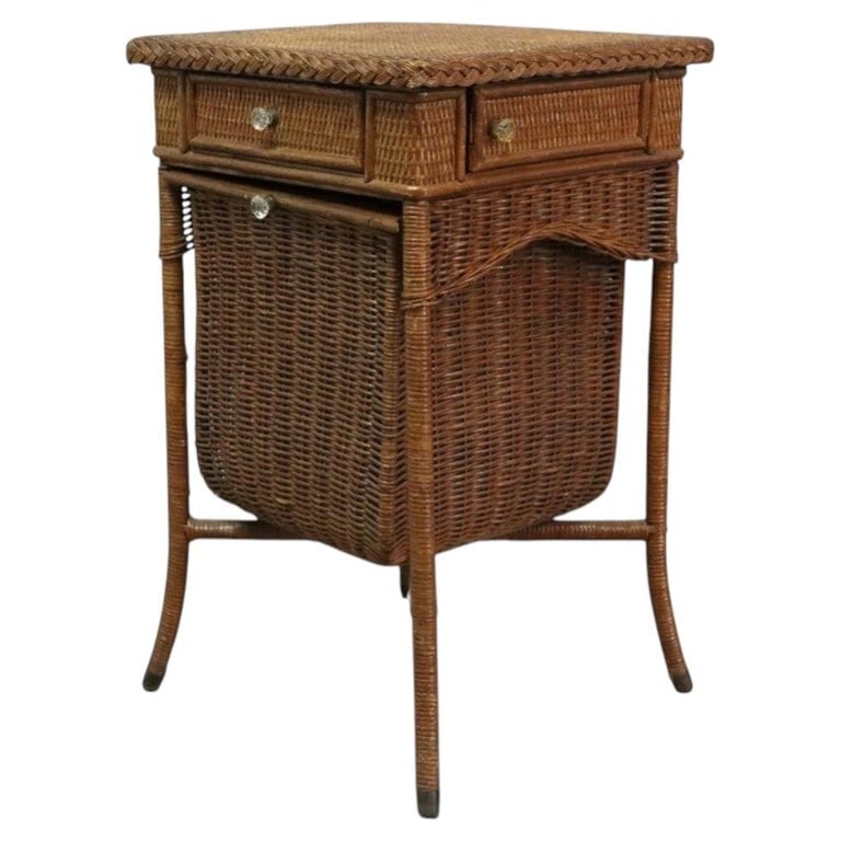Heywood Wakefield Wicker Sewing Stand C1920: This antique sewing stand, attributed to Heywood Wakefield, is crafted from woven wicker and dates to approximately 1920. The stand features a rectangular top with a braided wicker edge, two small upp