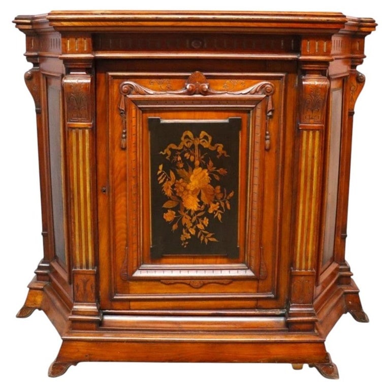 Renaissance Revival Ebonized Walnut Paneled Credenza With Marquetry Inlay c1880: An antique ebonized walnut credenza, dating to approximately 1880, showcases elaborate marquetry and inlay work. This piece features a central paneled door adorned with a detailed floral and ribbon mo