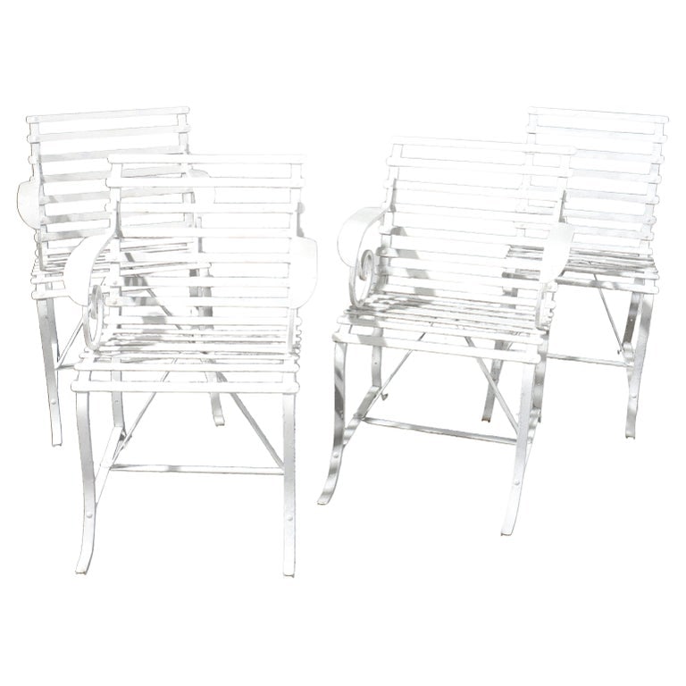 Four Arts & Crafts Painted Wrought Iron Garden Patio Chairs C1920: A set of four antique garden patio chairs from the Arts & Crafts period, circa 1920. These chairs are crafted from wrought iron and feature a painted finish. The design includes slatted seats and back