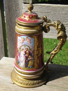 SUPERB ROYAL VIENNA DRINKING VESSEL: SUPERB ROYAL VIENNA DRINKING VESSEL SUPPORTED BY A BRONZE HANDLE IN THE FORM OF A FEMALE FIGURE. MOUNTED ON A FOLIATED DECORATED BASE OF BRONZE. FIELD OF TANKARD IS RED WITH GOLD GILT FOLIAGE WITH TWO