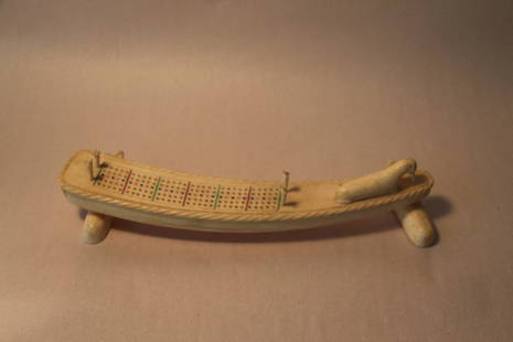 CARVED INUIT CURVED BONE CRIBBAGE BOARD: SUPPORTED ON TWO CARVED POLAR BEARS, A CARVED WALRUS SITS AT THE TOP OF THE ROPE BORDERED BOARD. EACH OF THE FOUR GAME PEGS ARE CARVED TO RESEMBLE ARCTIC FOXES UNSIGNED ACQUIRED BY CONSIGNOR, A GEOLOG