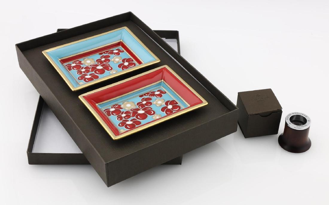 Patek Philippe 2pc Limoge Dish Set and Loop: Lot includes a Patek Philippe 2 piece Limoge dish set along with a Patek loop. Both with original boxes. Dishes measure 4 1/2" x 3 1/2". Please review all photos closely. Contact us for more deta