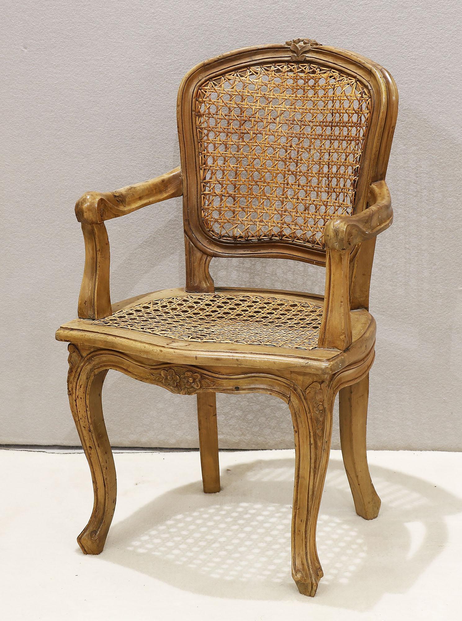 Childrens Wooden Arm Chair: Childrens wooden armchair featuring a caned back and bottom along with a carved floral design on the base. Measures 25 1/2" tall x 14 3/4" wide x 13" deep Please review all photos closely. The nonappe