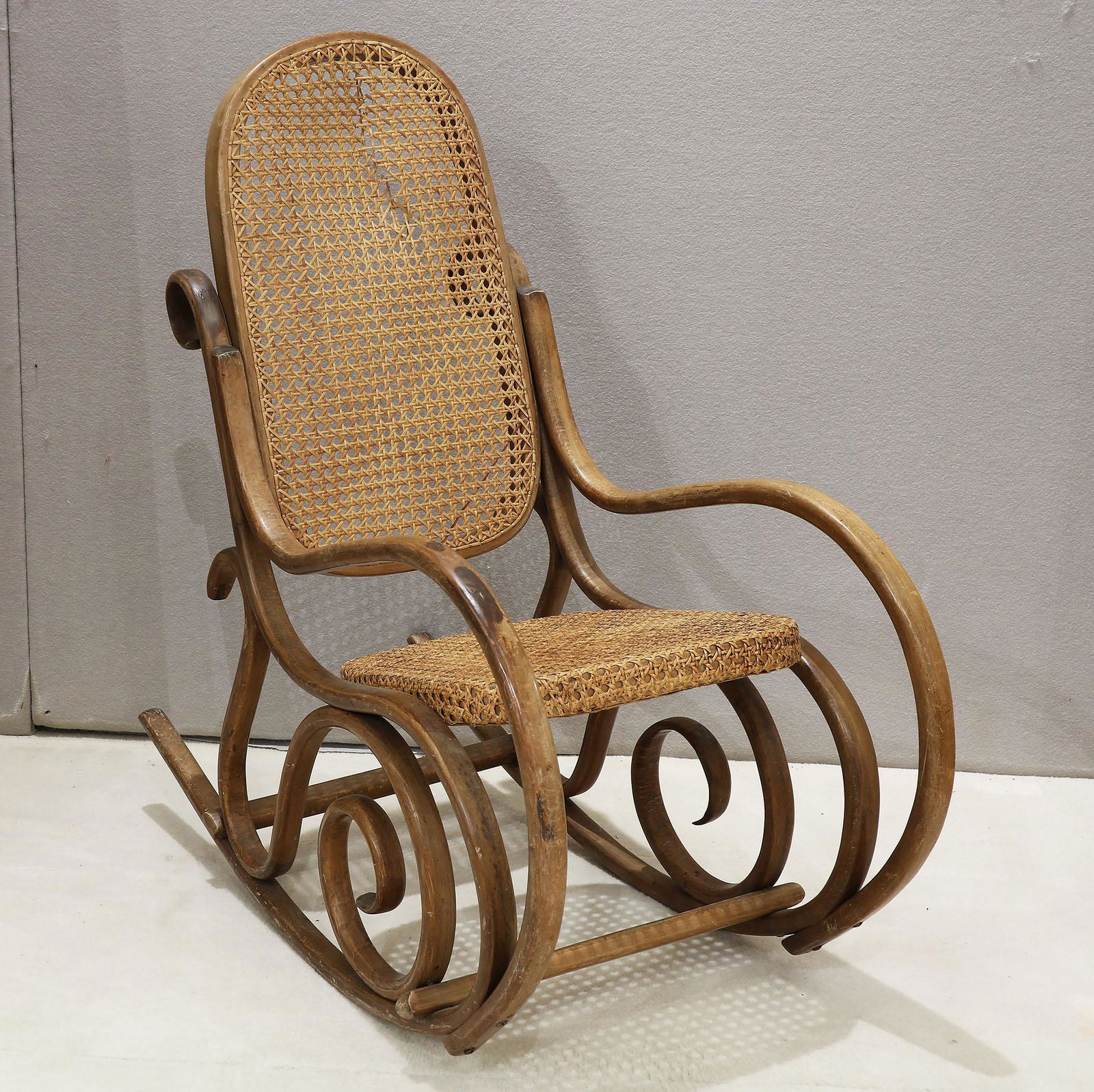 Childrens Wooden Rocking Chair: Childrens wooden rocking chair with a caned back and bottom. The back shows some breakage in the cane. Please see photos for close ups. Measures 31" tall x 14 3/4" wide x 31 1/2" deep. Please review a