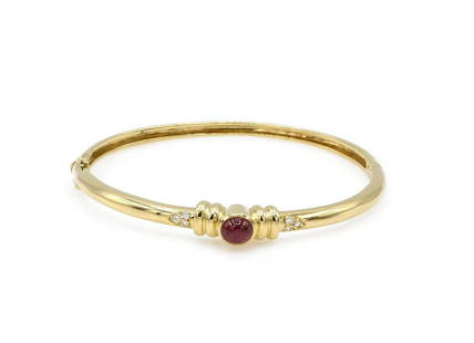 14K Yellow Gold Ruby and Diamond Bangle Bracelet: Bangle bracelet in 14k yellow gold featuring 1 ruby cabochon weighing approx 1.40ct with approx 0.06ctw of diamonds. Width ranges from 4mm-6mm, inner circumference measures approx 6.25", and it