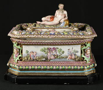 Large Capodimonte Porcelain Covered Dresser Box: Hand painted porcelain dresser box by Capodimonte. Features mythological figure motif with fruit and floral decoration throughout. Top of the box with the nude figure, there is a chip in the bottom