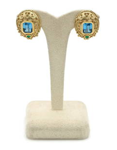14K Yellow Gold Blue Topaz and Emerald Huggie Earrings: Etruscan scroll design huggie earrings in 14k yellow gold featuring 2 blue topaz gemstones weighing approx 6.00ctw along with 2 emeralds weighing approx 0.40ctw. They are 28mm x 20mm and weigh 24.3