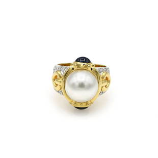 18K YG South Sea Pearl Sapphire & Diamond Cocktail Ring: Elegant cocktail ring in 18k yellow gold featuring an 11.8mm South Sea pearl accented with 2 sapphire cabochons weighing approx 1.60ctw, and 32 diamonds weighing approx 0.25ctw. The ring is 20mm wide