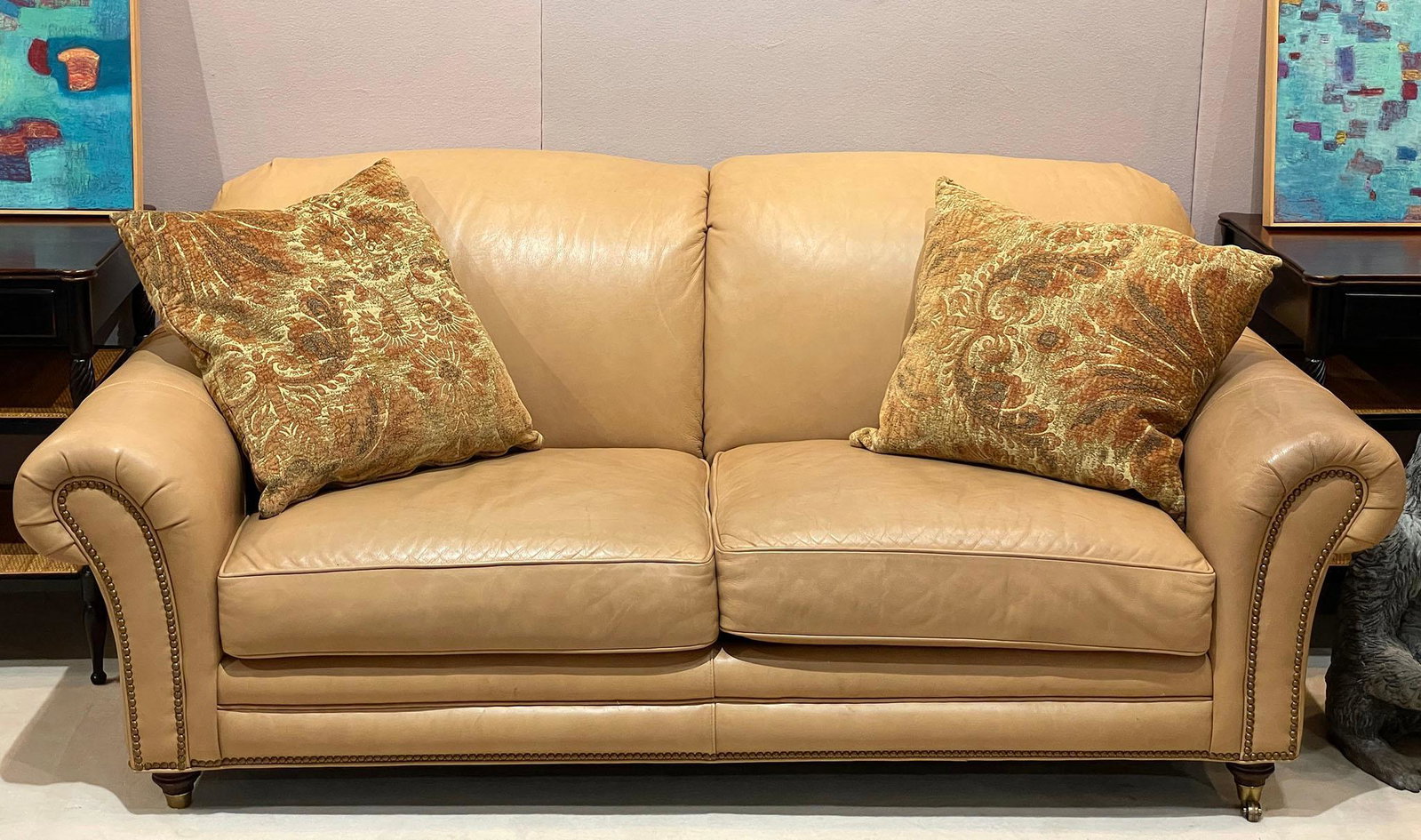 Robb & Stucky Leather Loveseat: Leather loveseat by Robb & Stucky with throw pillows. Shows some wear along with some small stains and pen marks. One of the front legs is missing its castor. Measures approx 33" h x 78.5"